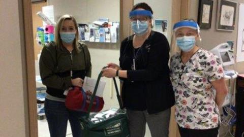 three women holding vaccine cooler