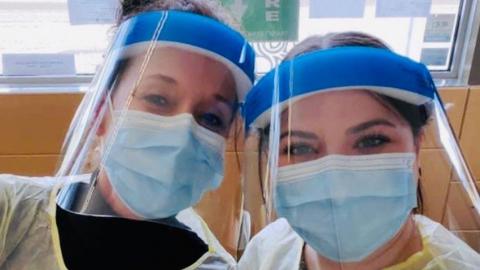 two women wearing masks and visors