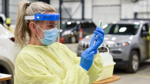 A nurse inserts a needle into a vial of the COVID-19 vaccine.