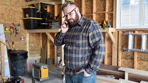 A man in his workshop is on the phone seeking mental health support.