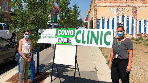 Immunizers pose with a sign advertising the North Battleford immunization clinic. 