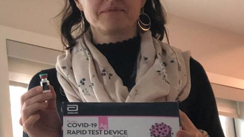 Dr. Julie Stakiw holding a COVID-19 rapid screening test kit.