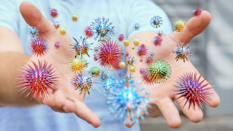 COVID germs float above a pair of open hands.