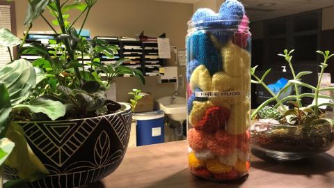 Knitted hearts fill a jar sitting on a hospital station.