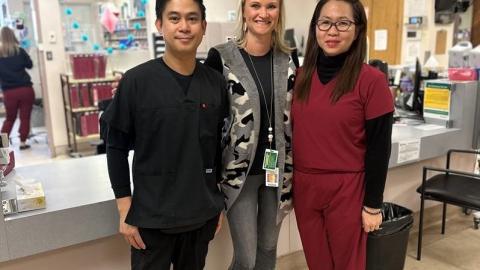 Three individuals posed together in front of the nursing station at Kindersley and District Health Centre.