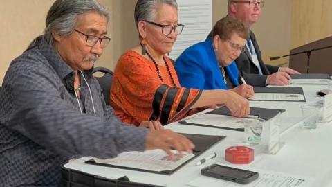 Knowledge Keepers Daniel Alphonse and Judy Pelly, SHA Board Chair Arlene Wiks, and SHA CEO Andrew Will sit at a table signing the SHA's reaffirmation of its commitment to Truth and Reconciliation.