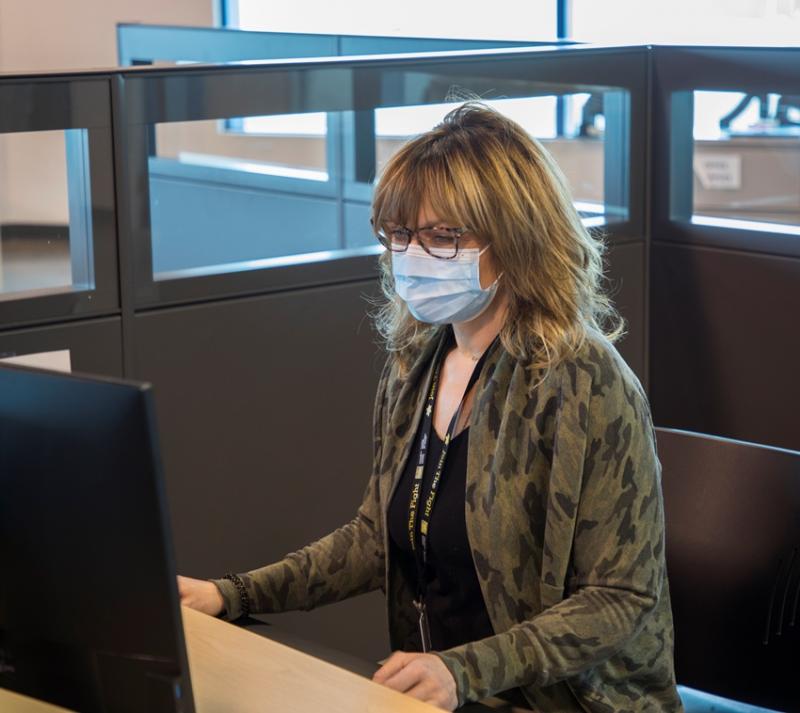 woman wearing mask sitting at computer