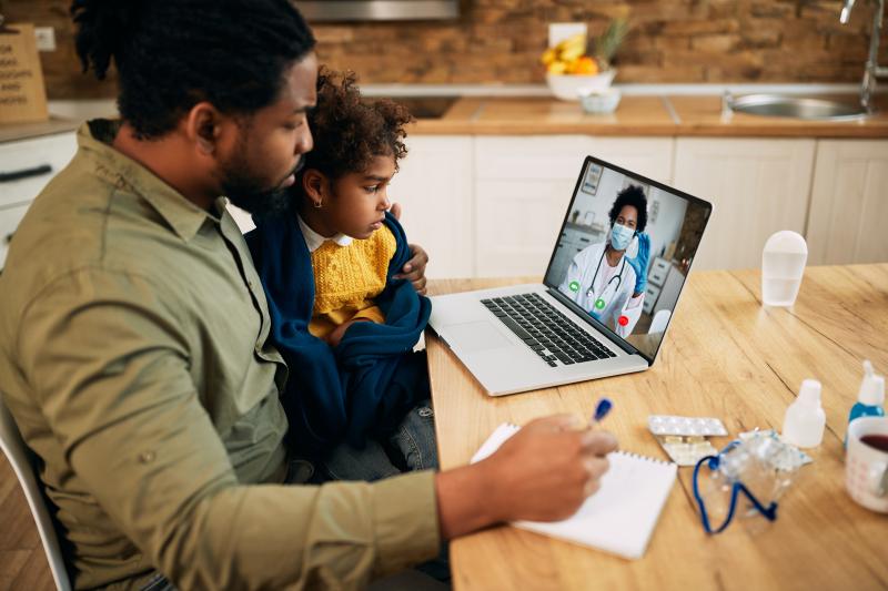 Man and child attending virtual appointment 