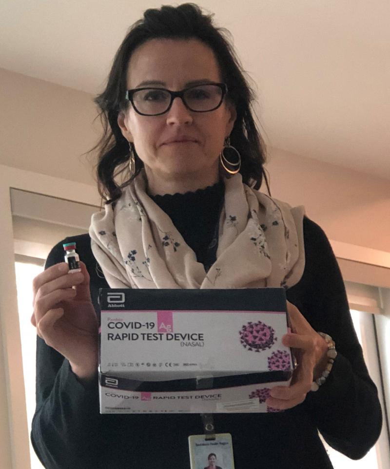 Dr. Julie Stakiw holding a COVID-19 rapid screening test kit.