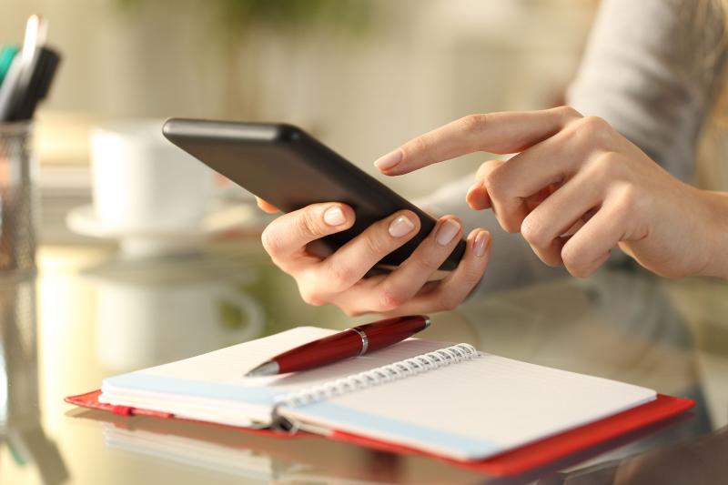 Hands hold a phone over a paper agenda.