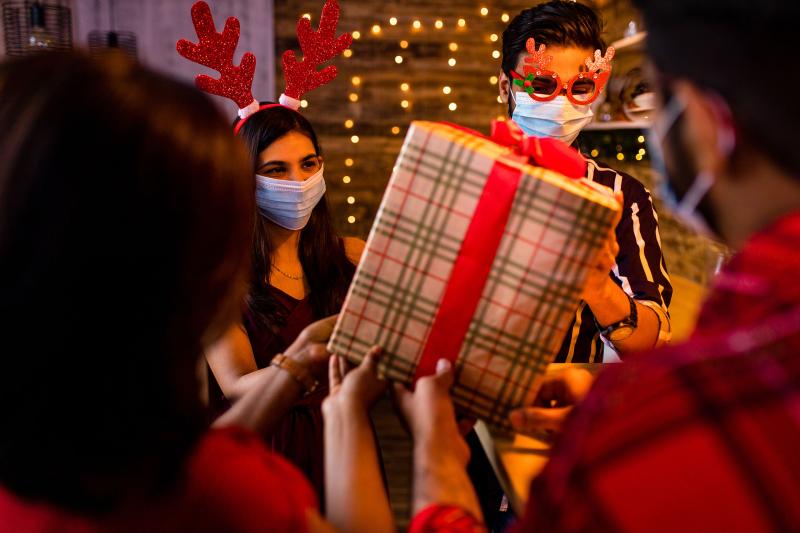 A group of people exchange presents while masked.