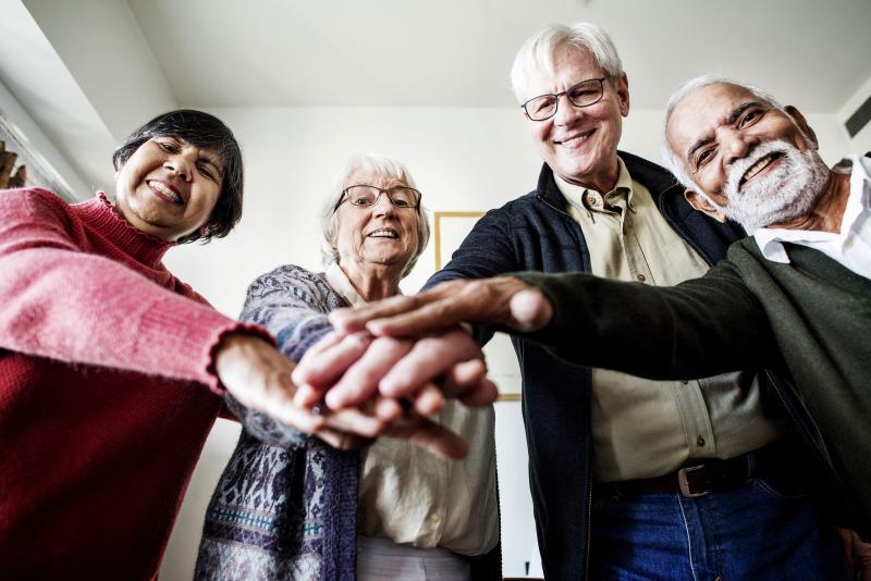 Four seniors smile as they put their hands together in fellowship.