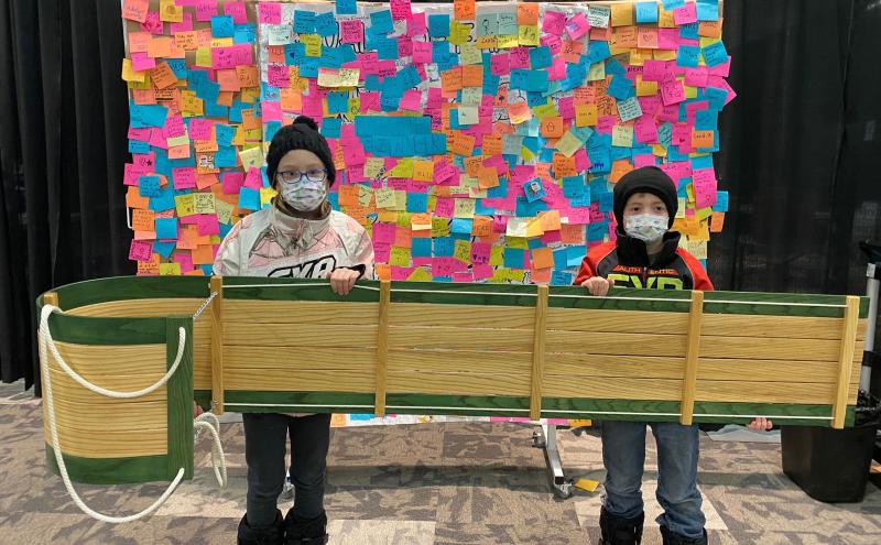 Two children hold a handmade toboggan they won at the Prairieland Park vaccine clinic in Saskatoon.