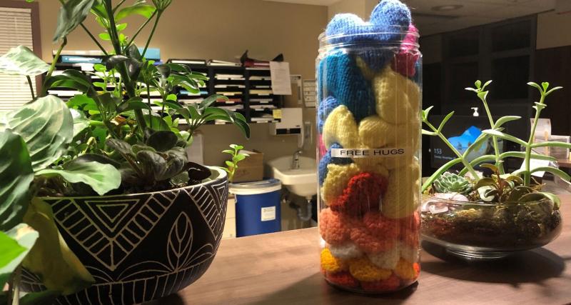 Knitted hearts fill a jar sitting on a hospital station.