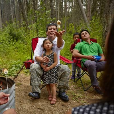 A dad and three children roast marshmallows at Great Blue Heron Provincial Park in Saskatchewan.