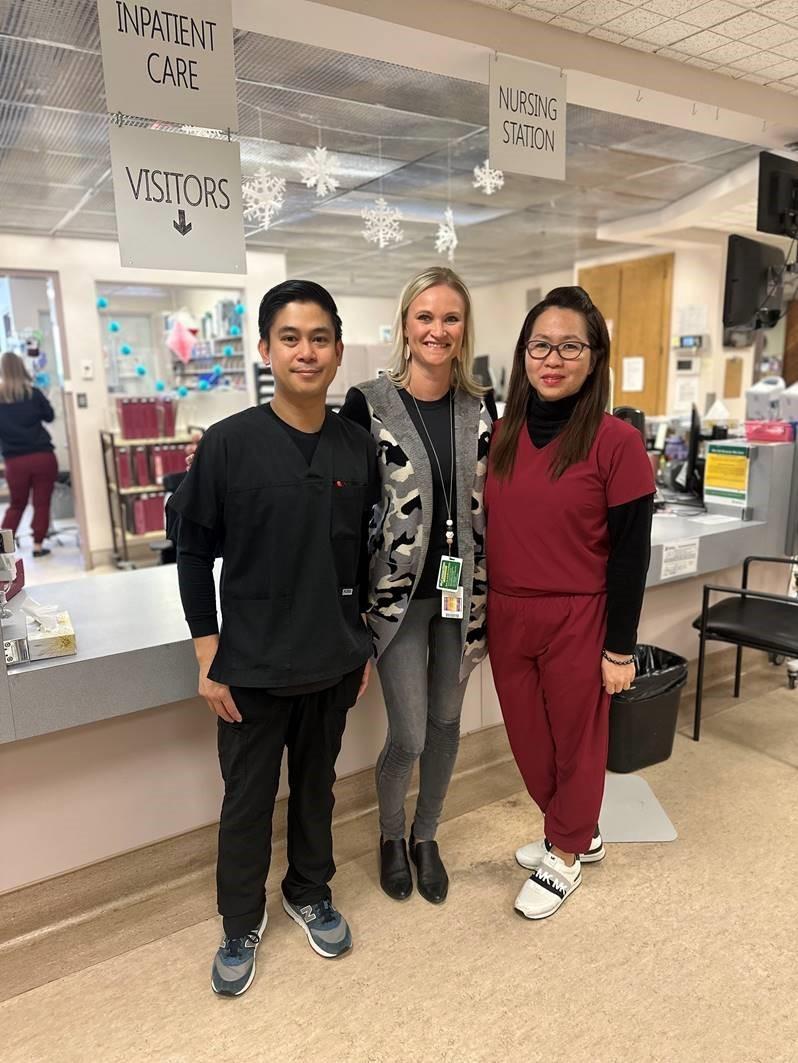 Three individuals posed together in front of the nursing station at Kindersley and District Health Centre.