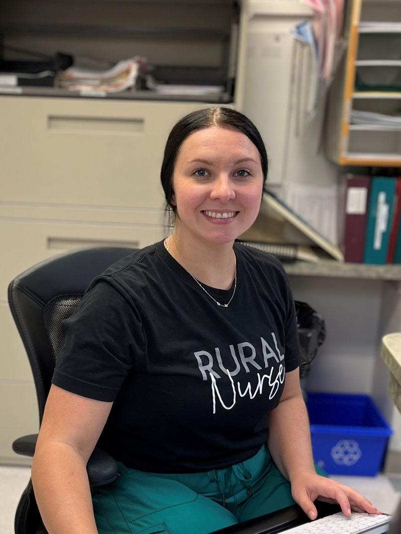 RN, Kashina Mahon, seated in front of a computer keyboard in the nursing station at Rosetown and District Health Centre.