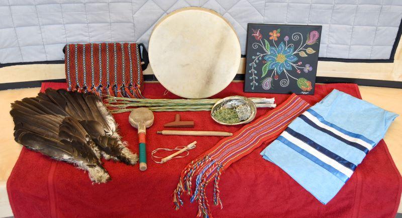 Indigenous medicines, clothing, and artwork displayed on a table